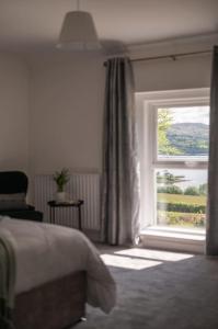 ein Schlafzimmer mit einem Bett und einem großen Fenster in der Unterkunft Eala House in Donegal