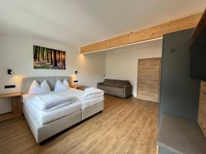 a bedroom with a large white bed and a couch at Apartment Apart Andrea by Interhome in Längenfeld