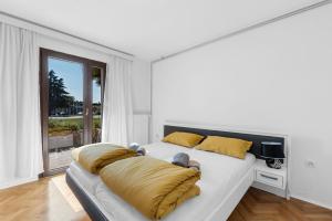 a white bedroom with a large bed with yellow pillows at APP Sandro with Common Pool in Poreč