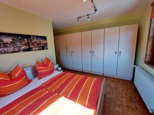 a bedroom with a bed with orange pillows and white cabinets at Apartment Erna by Interhome in Springstille