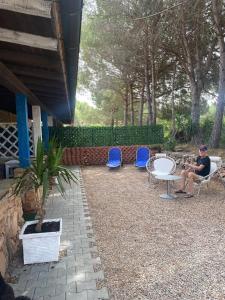 a man sitting in a chair next to two blue chairs at Le stanze del mare in Golfo Aranci