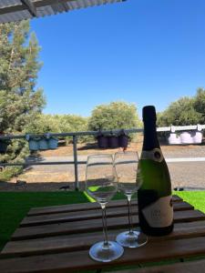 Una botella de vino y dos copas en una mesa. en heart of the golan heights cabin -בקתה במטע en Eli Ad