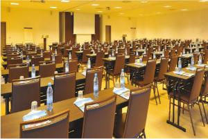 Movenpick Resort Lamantin Saly في سالي بورتودال: غرفة كبيرة مليئة بالطاولات والكراسي وعليها زجاجات