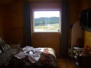 a bedroom with a window and a bed in front of it at Pousada Cristal Serra in Cambará