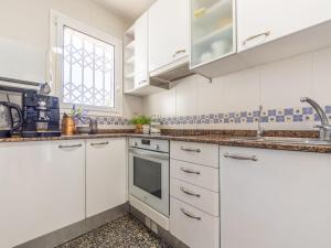 a white kitchen with white cabinets and a window at Holiday Home Oleg by Interhome in Torredembarra