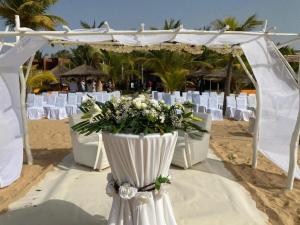 - une cérémonie de mariage sur la plage avec des chaises blanches dans l'établissement Movenpick Resort Lamantin Saly, à Saly Portudal