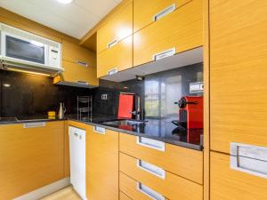 a kitchen with wooden cabinets and a microwave at Studio Alboran by Interhome in Salou