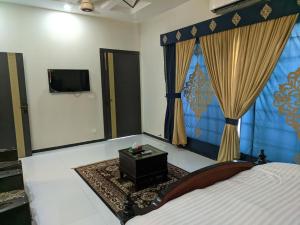 um quarto com uma cama, uma televisão e cortinas em White Palace Guesthouse em Islamabad