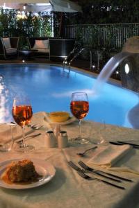 a table with two glasses of wine and a pool at Hotel La Pigna in Marina di Pietrasanta