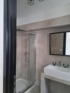 y baño con ducha acristalada y lavamanos. en Evita's Luxury Apartments, en Atenas