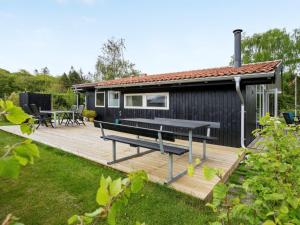 ein schwarzes winziges Haus mit einem Picknicktisch auf einer Terrasse in der Unterkunft Holiday Home Stiane - all inclusive - 100m to the inlet by Interhome in Børkop
