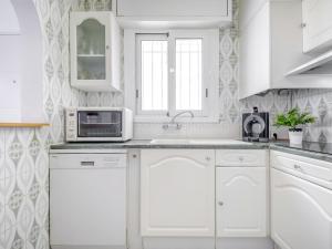 une cuisine blanche avec des armoires blanches et un micro-ondes dans l'établissement Apartment Bahia 58 by Interhome, à Empuriabrava