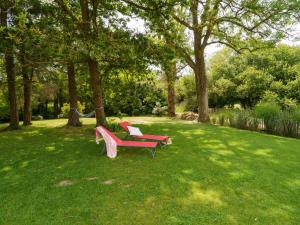twee rode banken in het gras in een park bij Holiday Home Penhors by Interhome in Plovan