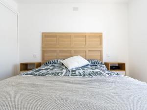 a bedroom with a large bed with a wooden headboard at Holiday Home Noelia by Interhome in Torredembarra
