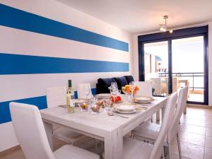 un tavolo con sedie bianche e un muro blu e bianco di Apartment Sueños del Mar I-3 by Interhome a Denia