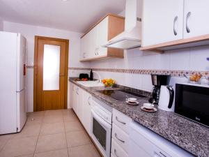 una cucina con armadi bianchi e piano di lavoro nero di Apartment Sueños del Mar I-3 by Interhome a Denia