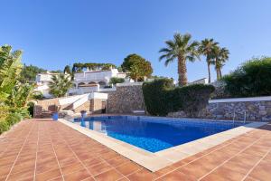 a swimming pool in a villa with palm trees at Casa Mariposa in Almuñécar