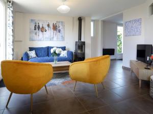 ein Wohnzimmer mit einem blauen Sofa und gelben Stühlen in der Unterkunft Holiday Home Le Moulin Neuf by Interhome in Pornic