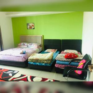 2 łóżka w pokoju z zielonymi ścianami w obiekcie Apartment Wakaf Che yeh w mieście Kota Bharu