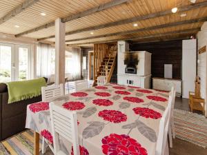 a dining room with a table with red flowers on it at Holiday Home Ateljee by Interhome in Rääkkylä