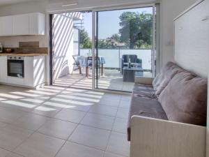Una sala de estar con un sofá y una vista de una cocina. en Studio Le Domaine de la Mer by Interhome, en Saint-Cyr-sur-Mer