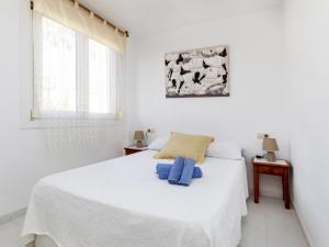 - une chambre dotée d'un lit blanc avec des oreillers bleus dans l'établissement Apartment Cala Gabriel by Interhome, à Vinaròs