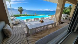 een terras met een tafel en stoelen en een zwembad bij Villa Kalamos, beachfront in Pogoniá