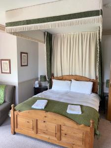 a bedroom with a canopy bed with two towels on it at Arrandale Lodge in Norwich