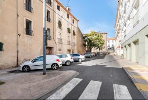 een rij geparkeerde auto's geparkeerd in een stadsstraat bij Appartement climatisé à Béziers avec Jacuzzi & Rétroprojecteur - Le Palais des Glaces in Béziers