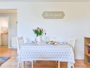 a white dining room table with white chairs and a sign that reads be cm guest at Apartment Edyvean by Interhome in Mevagissey