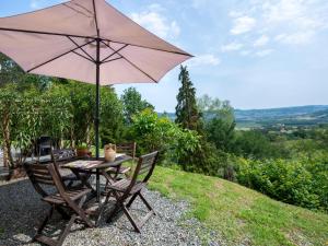 a table and chairs with an umbrella on a hill at Apartment Casa Domenica by Interhome in Monastero Bormida
