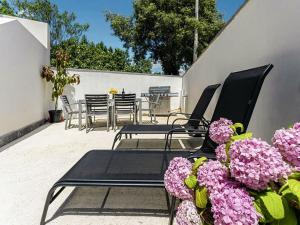d'une terrasse avec des chaises, des tables et des fleurs violettes. dans l'établissement Apartment Bura by Interhome, à Krnica