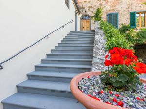 Un conjunto de escaleras con una maceta de flores rojas. en Apartment Casa Paolina by Interhome, en Greve in Chianti