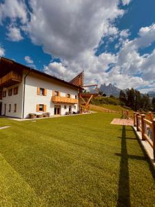 un edificio con un gran campo de césped delante de él en B&B Maso al Cervo en Fiera di Primiero