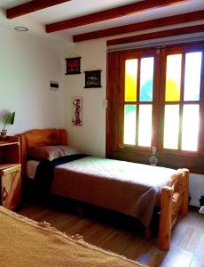 Cabaña Onty في إل كالافاتي: غرفة نوم بسريرين في غرفة بها نوافذ