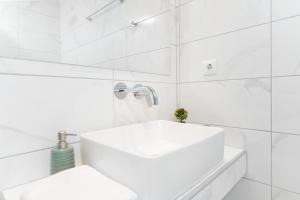uma casa de banho branca com um lavatório e azulejos brancos em Aenaon studios em Thásos