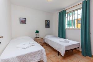 twee bedden in een kamer met groene gordijnen en een raam bij B18 - Village Street Apartment in Lagos