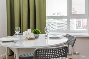a white table with chairs and wine glasses on it at Lux Apartment Umai in Astana