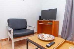 een woonkamer met een stoel en een tv bij B18 - Village Street Apartment in Lagos