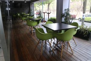 Hotel Diana del Bosque by DOT Urban في موريليا: صف من الطاولات والكراسي الخضراء في المطعم