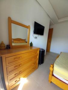 a bedroom with a dresser with a mirror and a bed at Bel Appartement à Mansbay in Mansouria