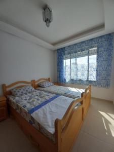 a bedroom with a wooden bed with a window at Bel Appartement à Mansbay in Mansouria