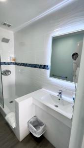 Baño blanco con lavabo y espejo en Dover Beach Hotel en Christ Church