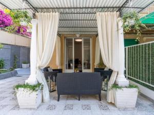eine Terrasse mit weißen Vorhängen sowie einem Tisch und Stühlen in der Unterkunft Apartment Giardino al Mare by Interhome in Sanremo