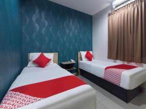 two beds in a room with blue and red at Hotel Pinji in Ipoh