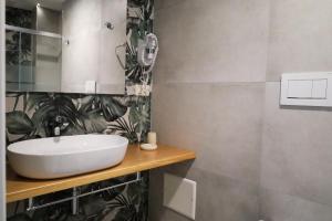 a bathroom with a white sink and plants on the wall at Hermitage Suites in Sassari
