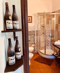 baño con ducha y estanterías con botellas en Madama Langa Country House con piscina nelle vigne, en Montelupo Albese