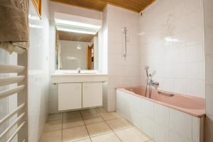 uma casa de banho com uma banheira rosa e um lavatório. em Chalet Poupette em Morzine