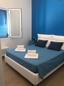 Un dormitorio azul con una cama con toallas. en Blue Velvet, en Punta Secca