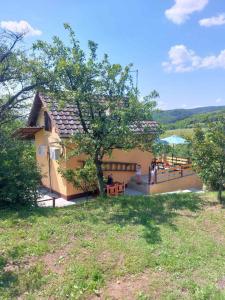 a building with a tree and a table and benches at Marley kuca za odmor in Bešenovački Prnjavor